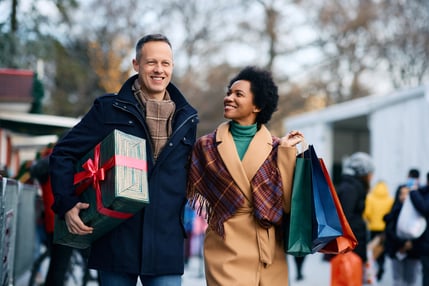 Couple shopping together with presents and bags. They are outside.