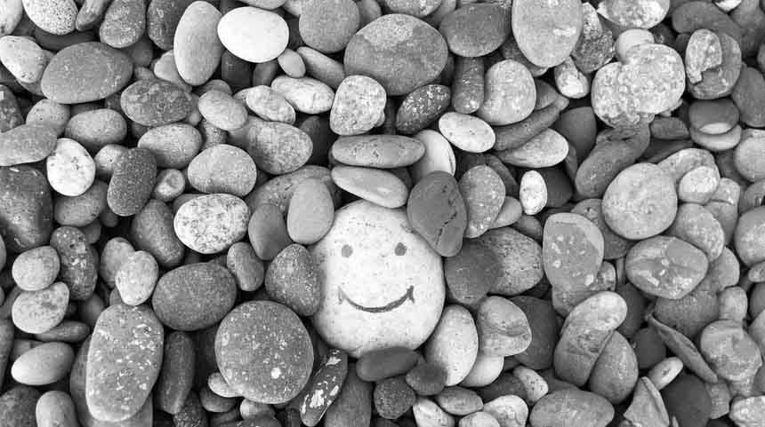 Smiley face drawn in rocks, black and white photo.
